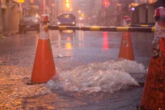 Orange cones around overflowing manhole during typhoon