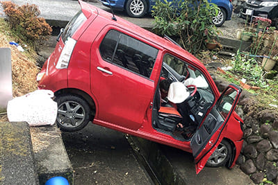 車は用水路の両側の壁の間にすっぽりとはまりこみ、宙に浮いた状態