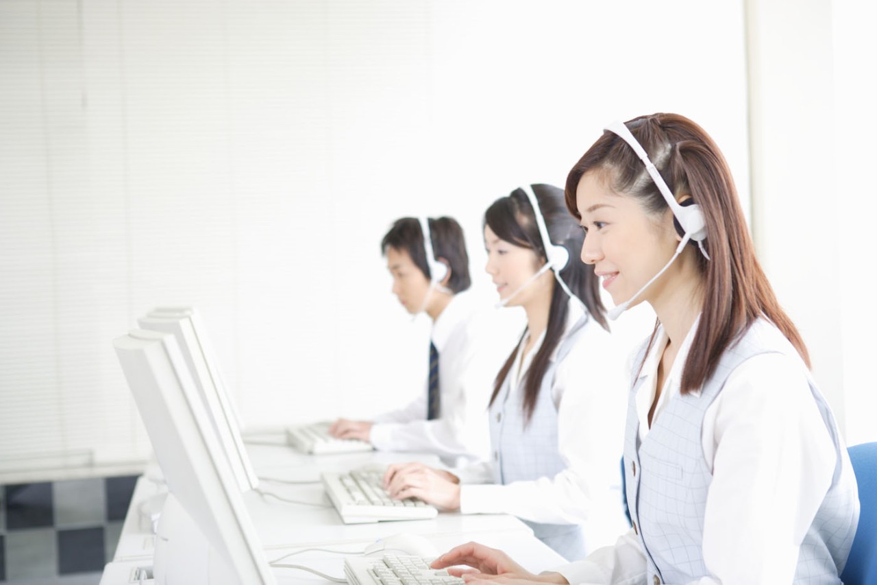 Three young adults with headsets working on computer